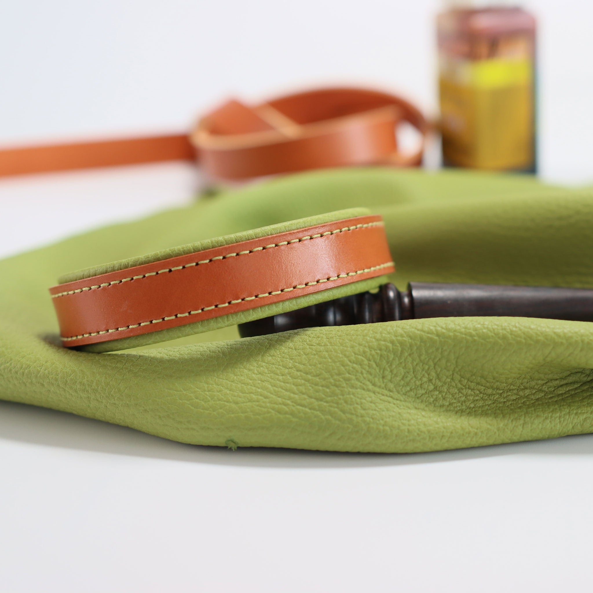 Exklusives Lederhalsband Natur-Grün liegend auf dem grünen Hirschleder mit Lederwerkzeug