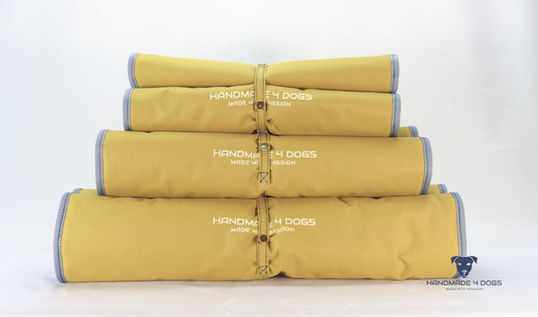 aufgerolltes-handgefertigtes-Hunde-Reisebett-von-handmade-4-dogs-in-der-Farbe-Senf-mit-wedgwood-farbiger-Einfassung-und-einer-Liegefläche-aus-dunklem-Denim