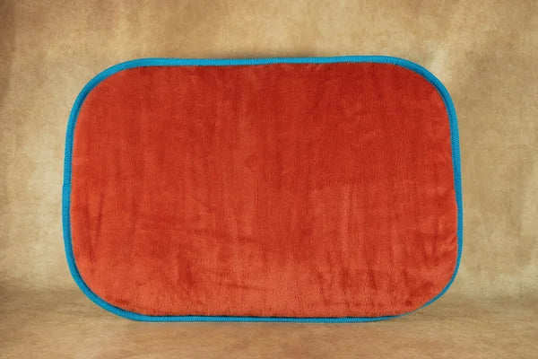 handgefertigtes-hunde-reisebett-von-handmade-4-dogs-gerollt-in-der-Farbe-türkis-mit-einer-kuscheligen-liegefläche-in-der-Farbe-Blutorange-einem-weichen-und-armen-orangeton