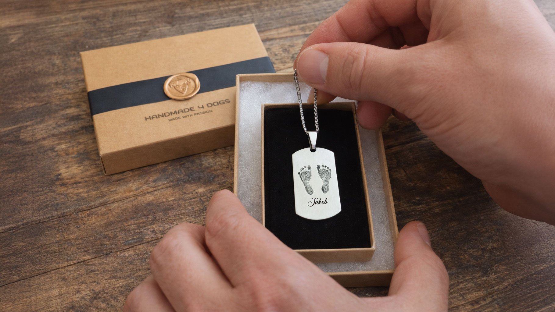 unboxing foto von graviertem Edelstahlanhänger mit gravierten Babyfüßen