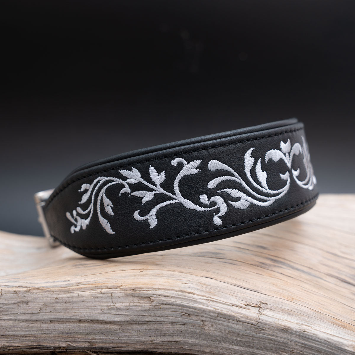 Schrägansicht des schwarzen Nappaleder-Halsbands mit silberner Ornamentstickerei und gebugten Kanten.