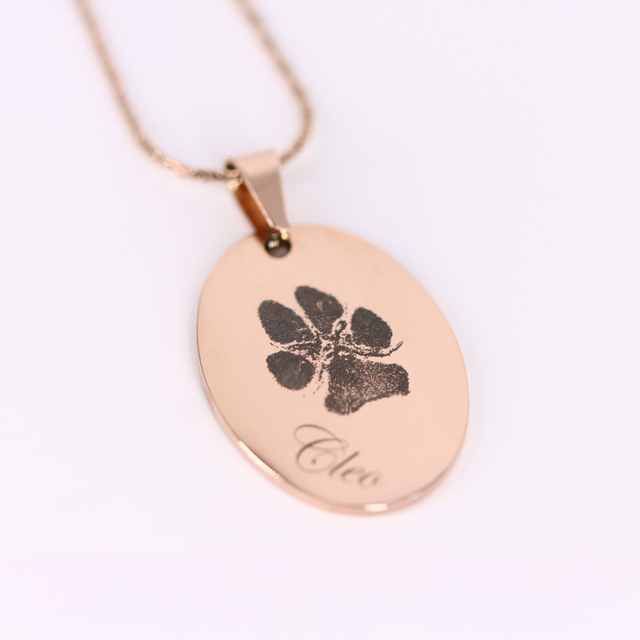 Nahaufnahme einer tiefengravierten Hundepfote mit Name Cleo auf Roségold