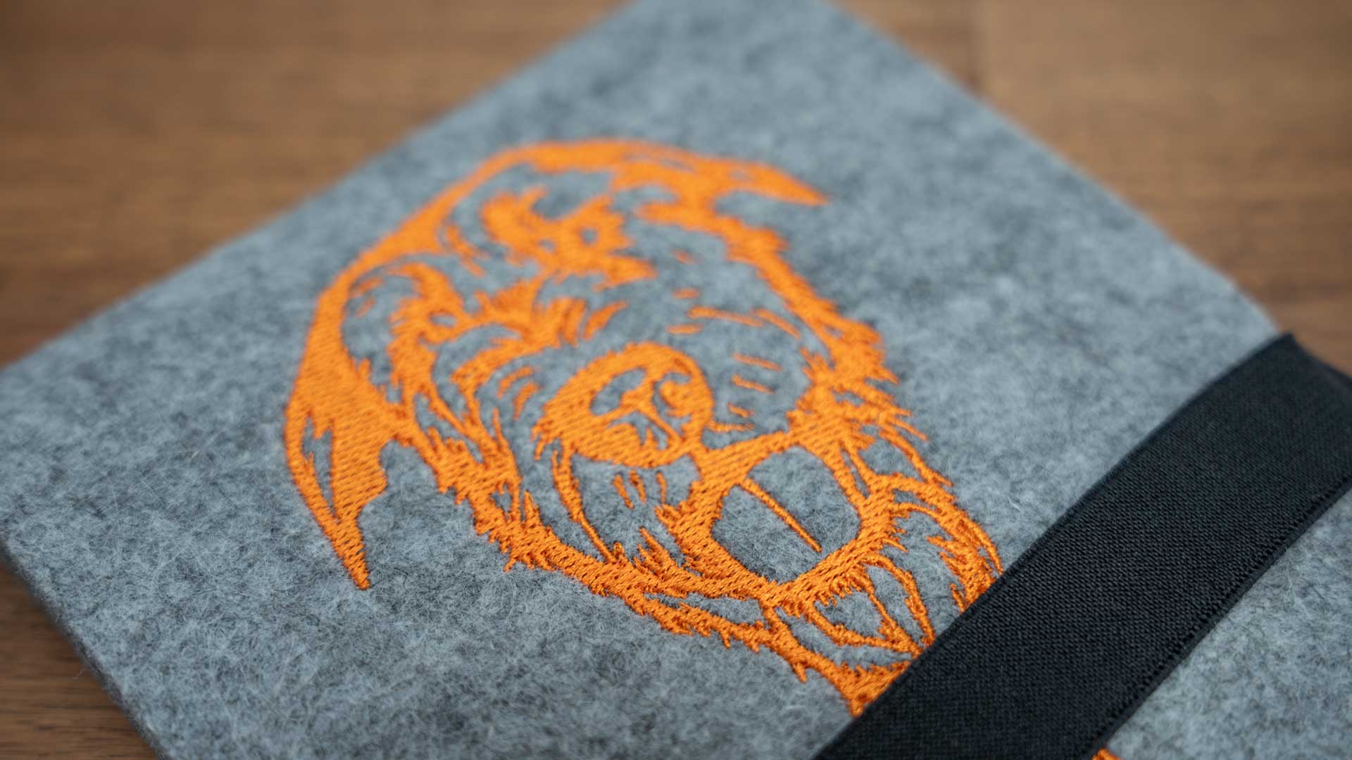 Detail der Irish-Wolfhound-Stickerei in Orange auf grauem Wollfilz