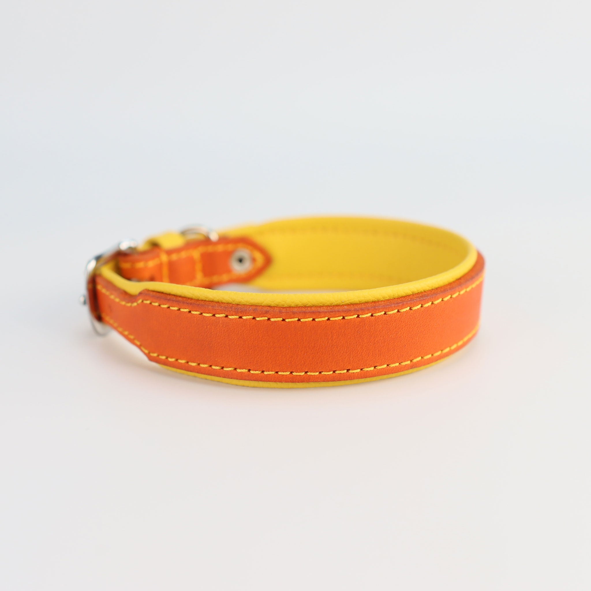 Handgefertigtes Hundehalsband aus orangem Fettleder mit gelber Nappa-Polsterung und gelber Kontrastnaht von der seite gesehen