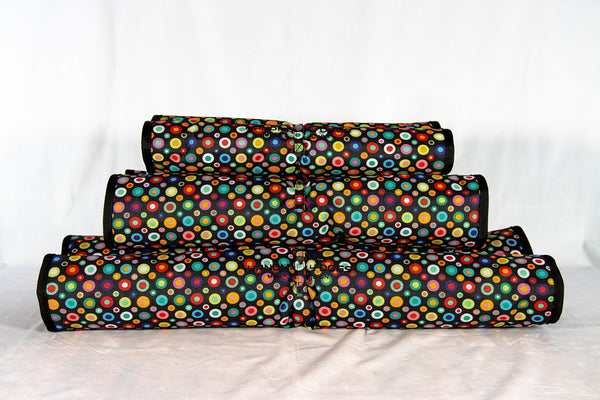 handgefertigtes-hunde-reisebett-von-handmade-4-dogs-im-gerollten-modell-das-Hundereisebett-ist-mit-vielen-bunten-punkten-am-aussenmaterial-überzogen-eingefaßt-ist-es-schwarz-und-innen-bildet-ein-122-unzen-denim-die-4cm-dicke-liegefläche