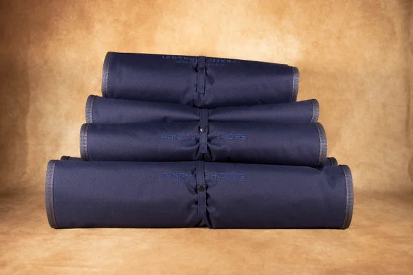 navy-farbenes-handgefertigtes-Hund-Reisebett-in-der-gerollten-version-mit-einer-dunkel-grauen-Liegefläche-mit-wabenmuster-eingefaßt-ist-dieses-handgefertigte-hunde-reisebett-in-dunkel-grau