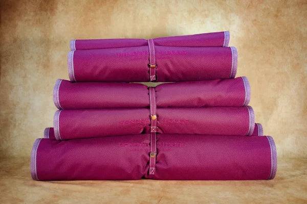 aufgerolltes-Hunde-Reisebett-handgefertigt-von-handmade-4-dogs-in-der-Farbe-brombeere-mit-altrosa-einfassung-und-einner-Liegefläche-in-altrosa-mit-Sternendesign