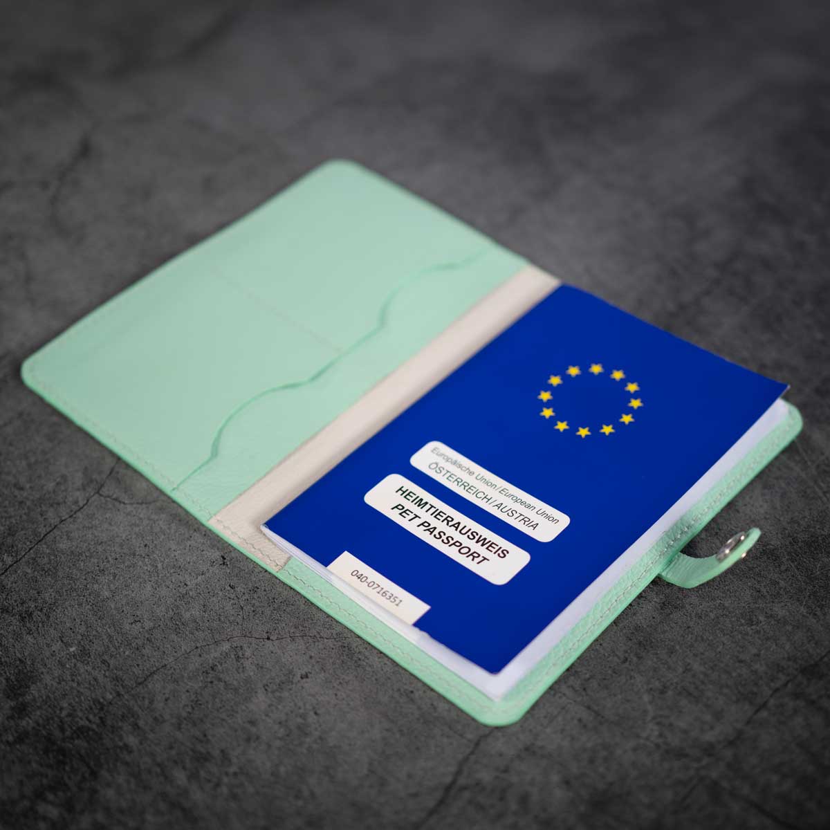 Geöffnete mintgrüne Lederhülle, befüllt mit einem blauen EU-Heimtierausweis auf der rechten Seite und sichtbaren Kartenfächern links
