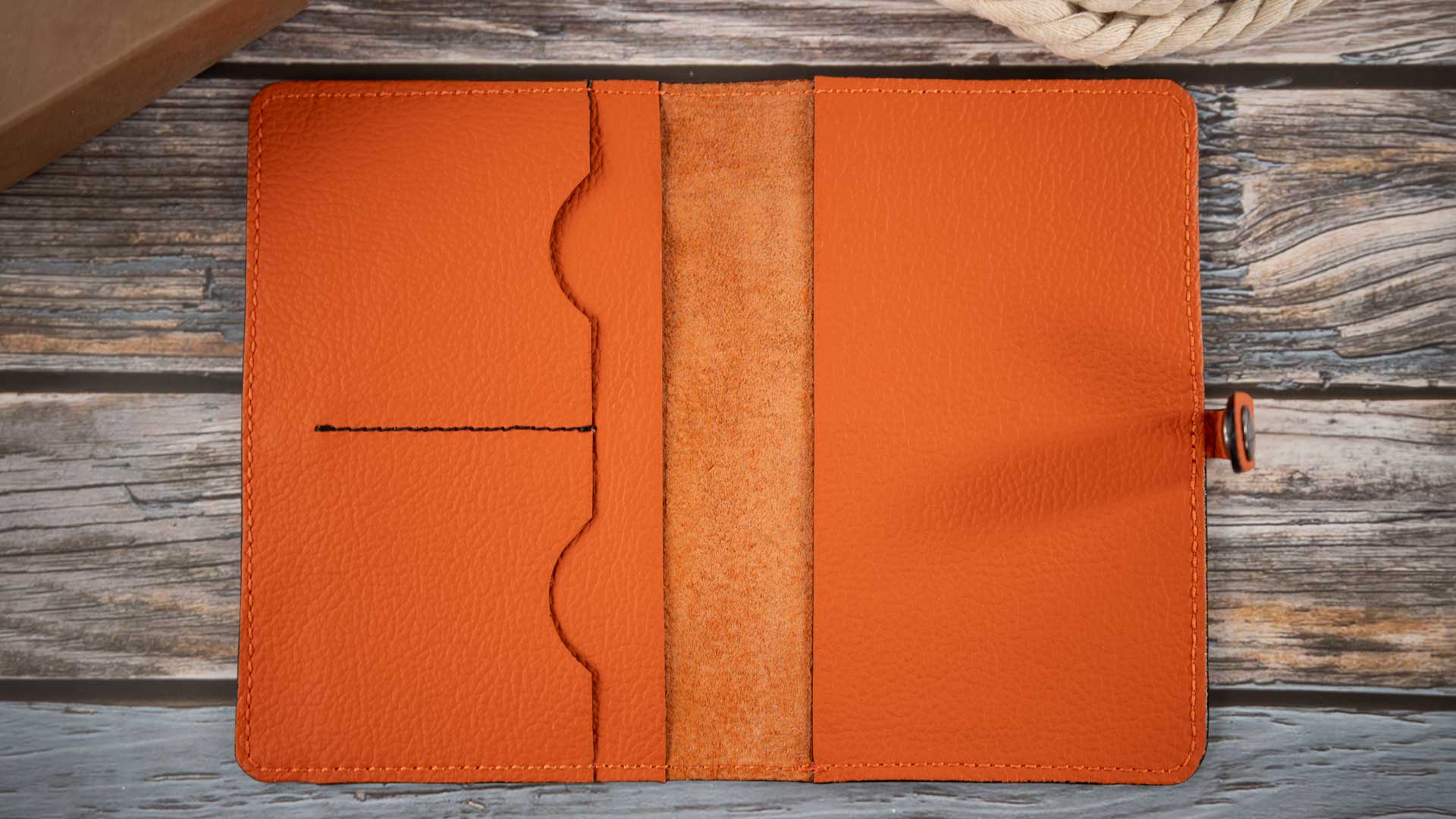 Innenansicht der geöffneten, noch leeren Heimtierausweishülle in leuchtendem Orange mit schwarzen Kontrastnaht und abgenähten Kartenfächern.