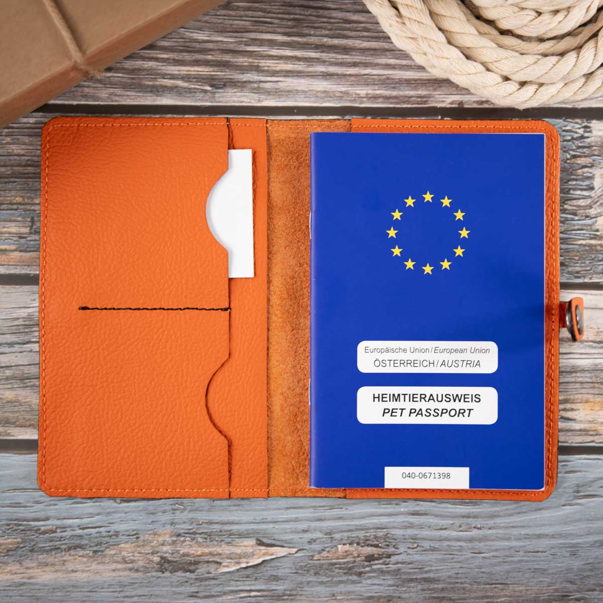 Geöffnete orangefarbene Leder-Impfpasshülle, befüllt mit einem blauen EU-Heimtierausweis und Sicht auf die praktische Fächeraufteilung
