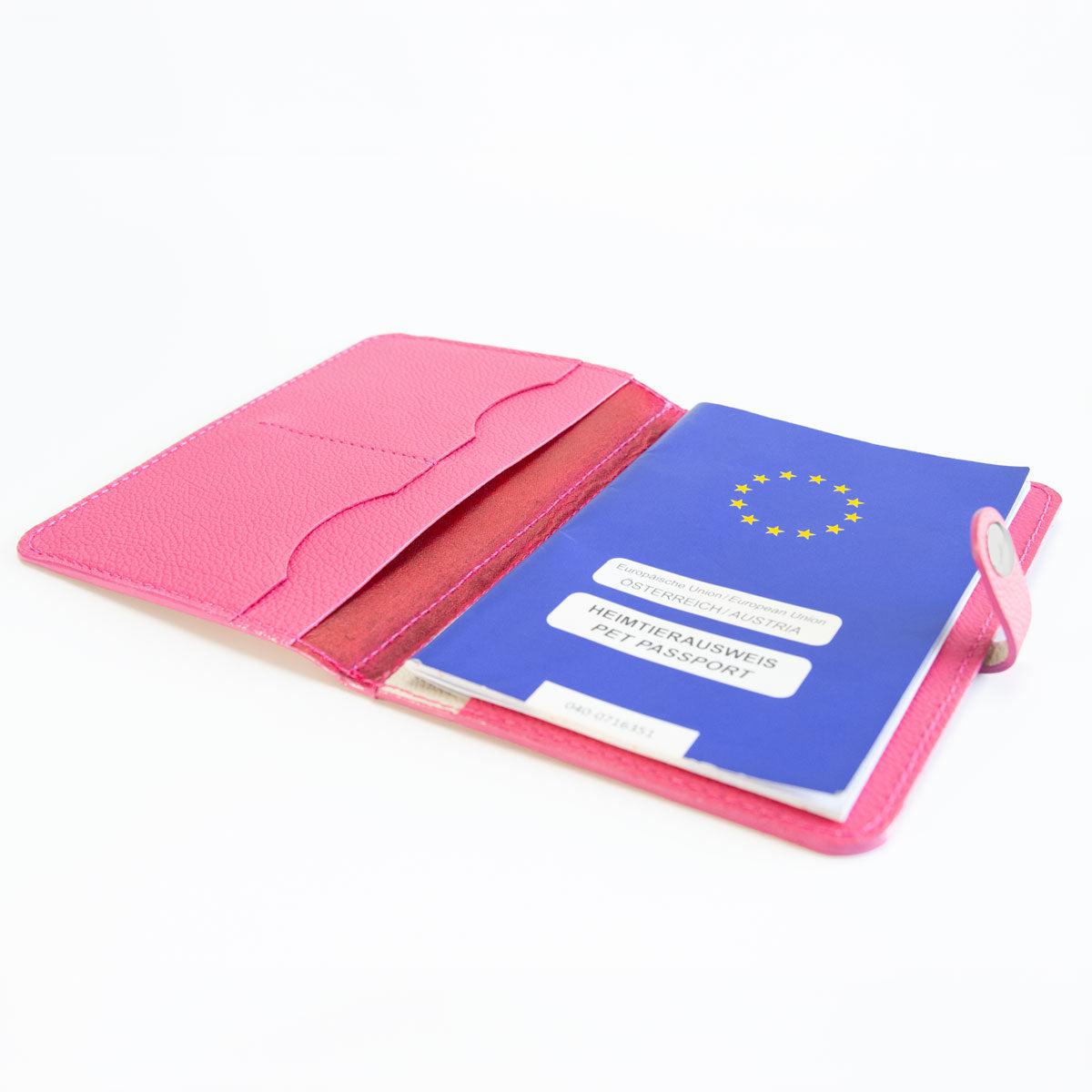 Geöffnete pinke Heimtierausweishülle in exotischer Schlangenoptik, befüllt mit einem blauen EU-Heimtierausweis und Tierarztunterlagen
