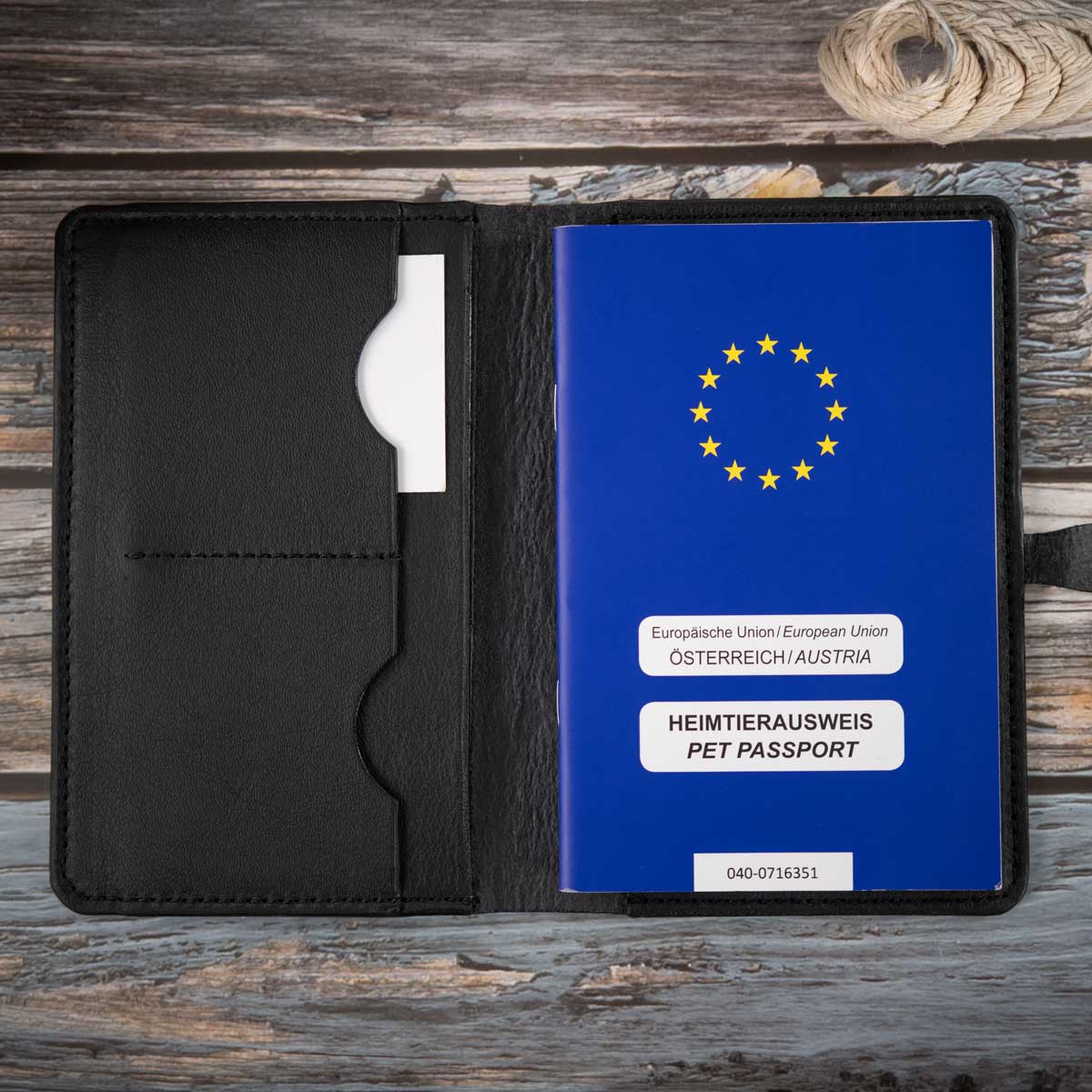 Geöffnete ungefütterte Lederhülle in Schwarz, befüllt mit einem blauen EU-Heimtierausweis und Sicht auf die praktische Fächeraufteilung