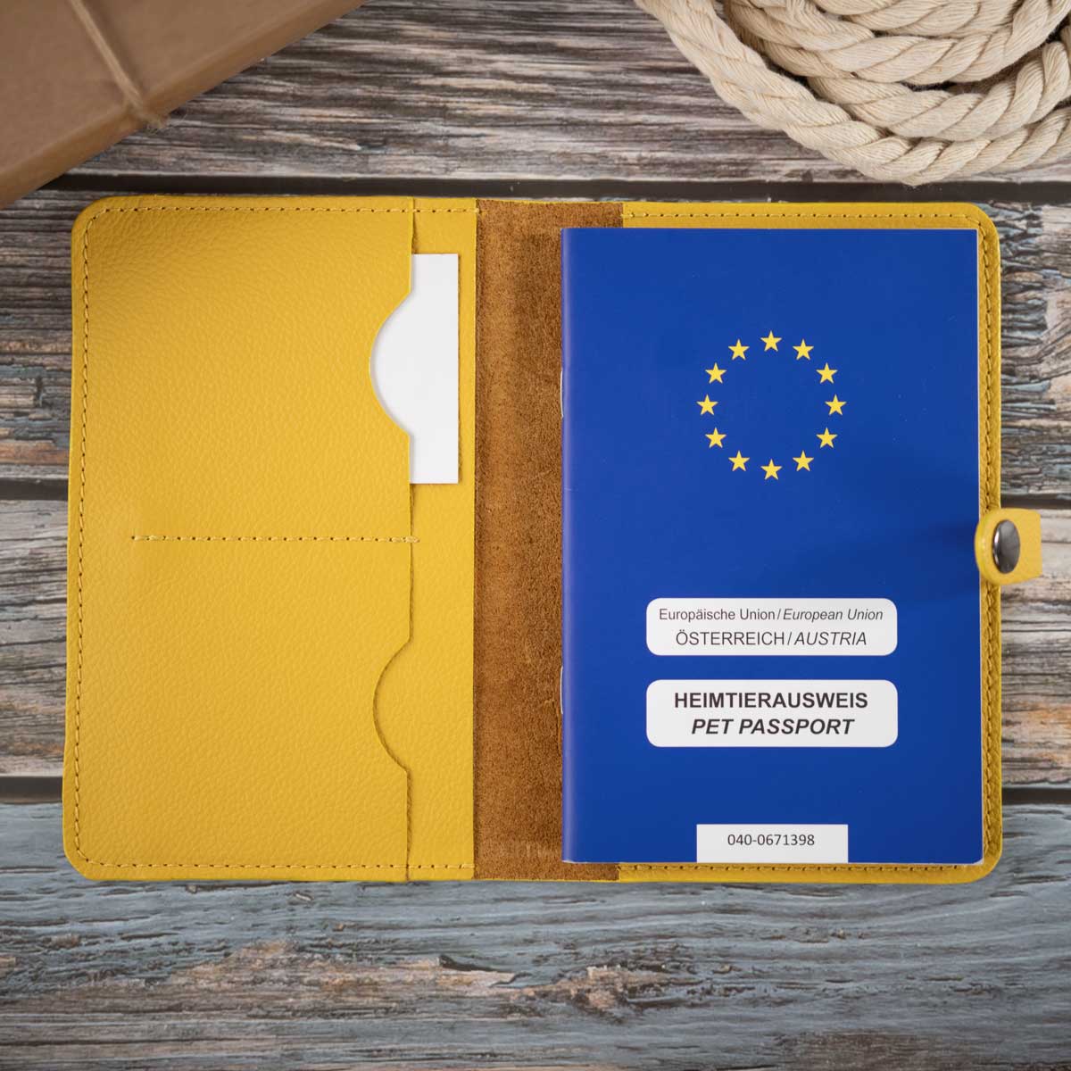 Geöffnete sonnengelbe Heimtierausweishülle aus Leder, befüllt mit einem blauen EU-Heimtierausweis und Sicht auf die praktische Fächeraufteilung.