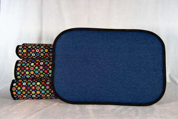 handgefertigtes-hunde-reisebett-von-handmade-4-dogs-im-gerollten-modell-das-Hundereisebett-ist-mit-vielen-bunten-punkten-am-aussenmaterial-überzogen-eingefaßt-ist-es-schwarz-und-innen-bildet-ein-122-unzen-denim-die-4cm-dicke-liegefläche