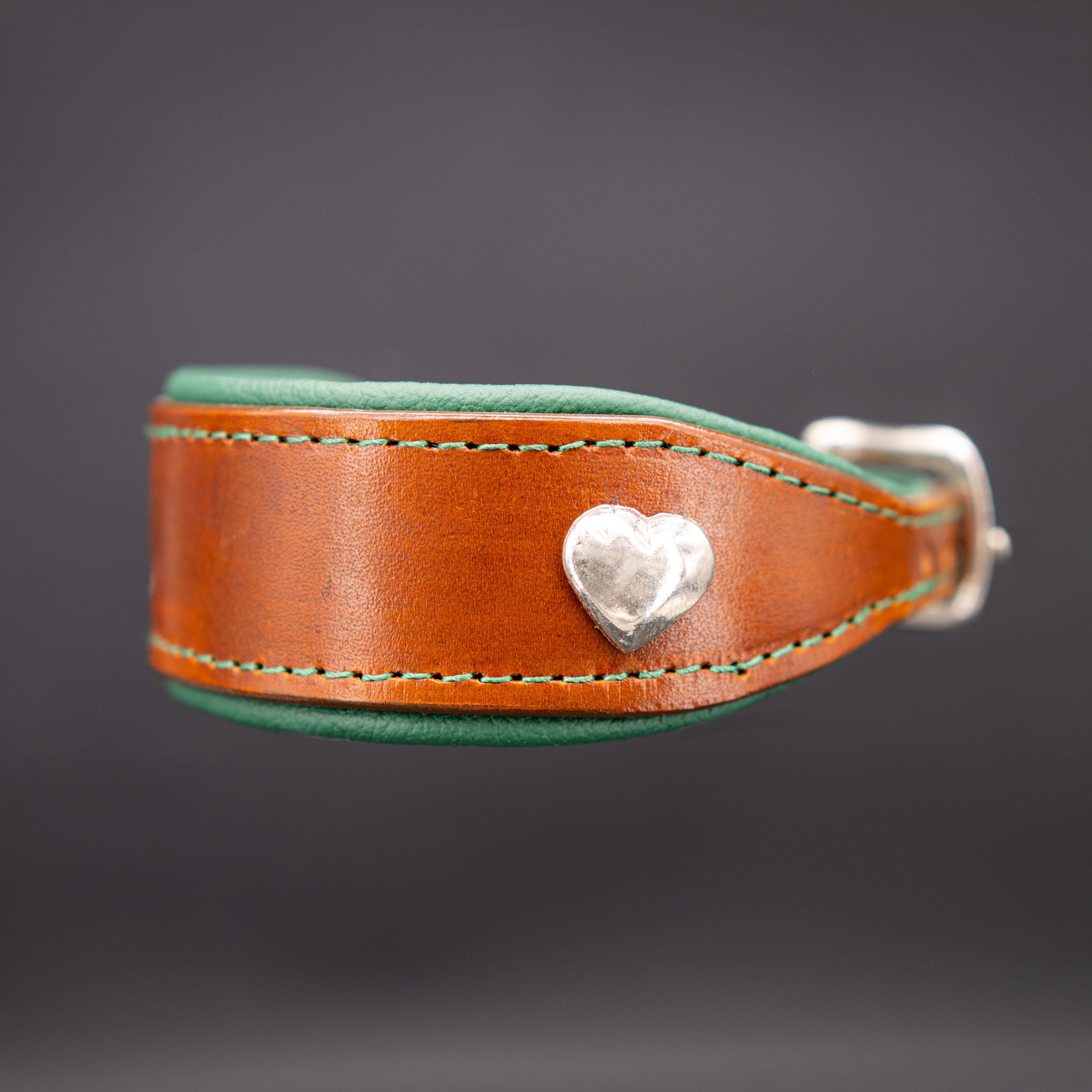 Nahaufnahme des Herz-Beschlags auf dem handgefärbten cognacfarbenen Lederriemen