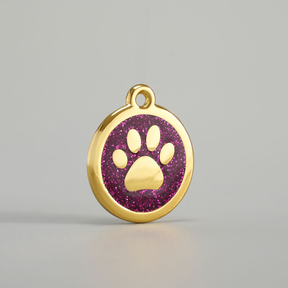 Goldene Hundemarke mit erhabener Pfote und magenta Glitzer-Epoxidharz-Hintergrund
