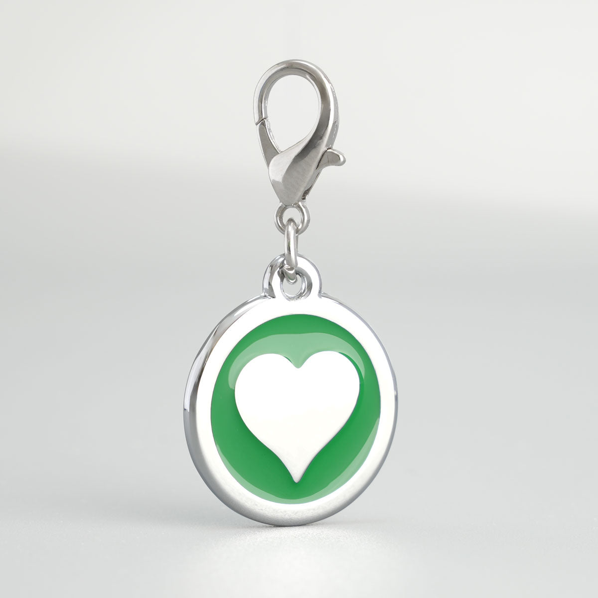 Detailansicht einer grünen, runden Hundemarke aus verchromtem Druckguss mit silbernem Herz-Inlay und Karabiner
