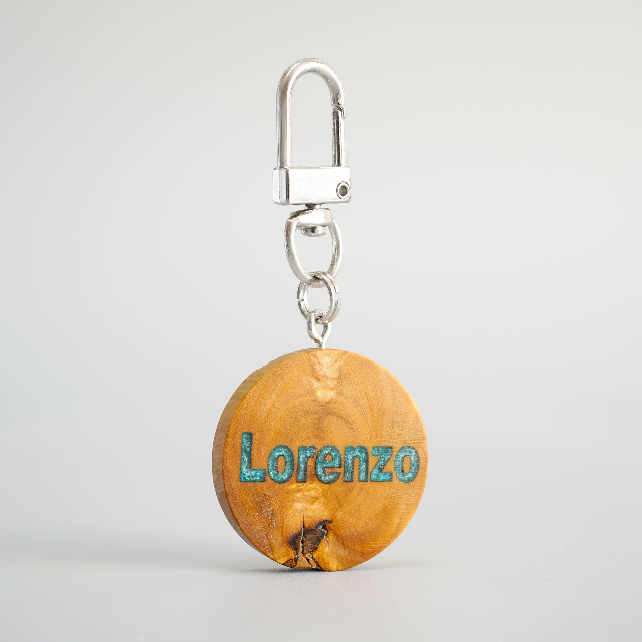 Detailansicht der Olivenholz-Hundemarke „Lorenzo“ mit blauem Epoxy-Inlay und silbernem Karabiner.