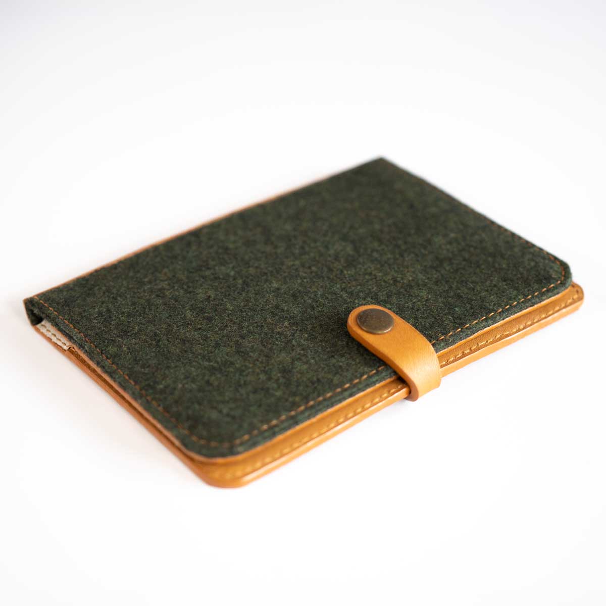 Schräge Ansicht der handgefertigten Leder-Loden-Hülle, die die harmonische Materialkombination aus Merinoloden und Rindsleder zeigt.