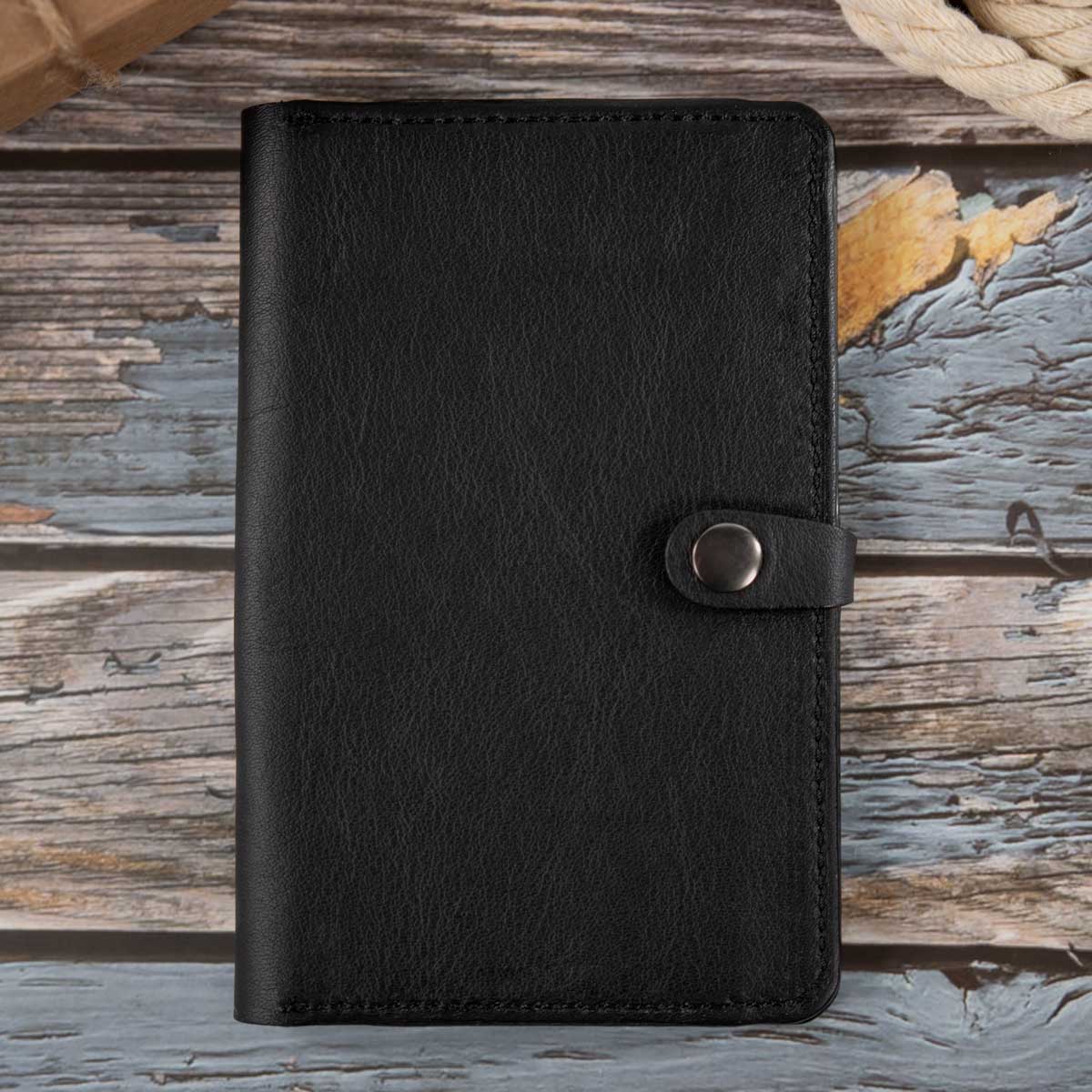 Vorderseite der geschlossenen, ungefütterten Leder-Heimtierausweishülle aus schwerem schwarzem Leder mit Verschlusslasche und Gunmetal-Druckknopf.