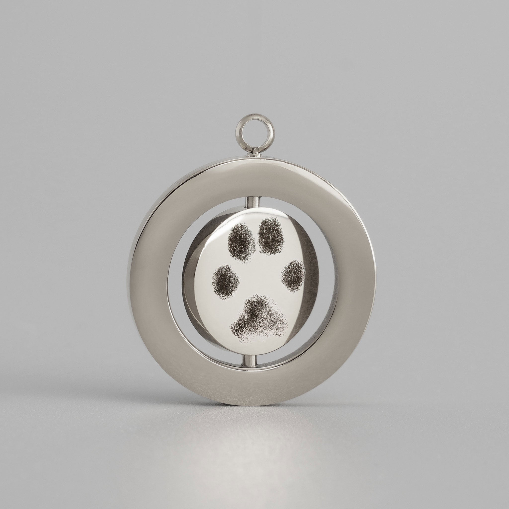 Silbernes Drehmedaillon mit detaillierter Pfotenabdruck-Gravur eines Hundes