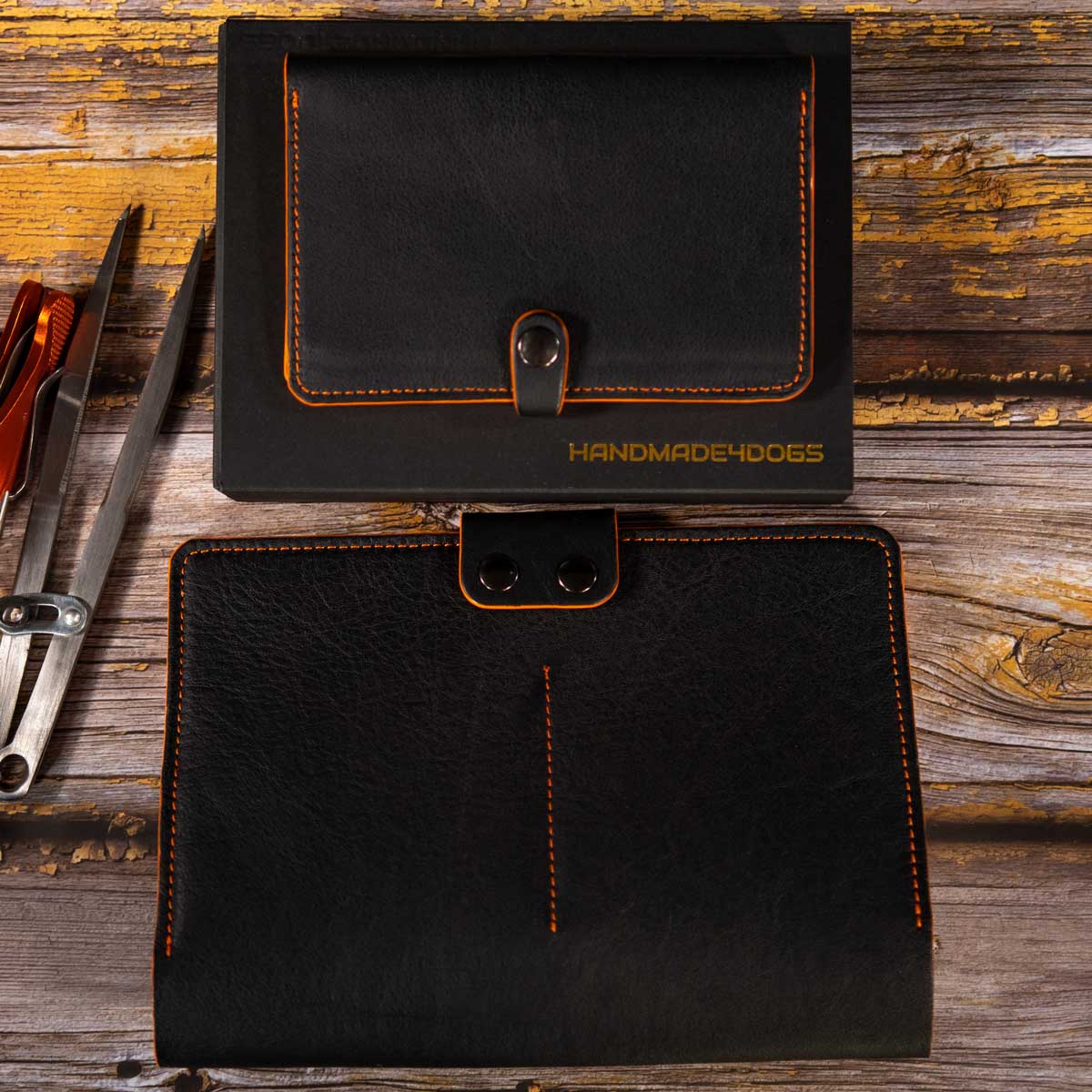 Die schwarze Impfpasshülle mit orangefarbenen Details und das dazugehörige Travel Wallet, exklusiv präsentiert auf dem edlen schwarzen Schiebekarton mit Logoprägung.