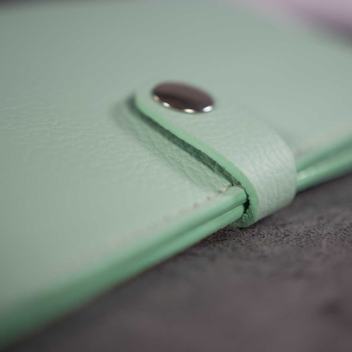 Detailaufnahme der präzisen Naht und des butterweichen Off-White Kalbslederfutters im Inneren der mintgrünen Hülle.