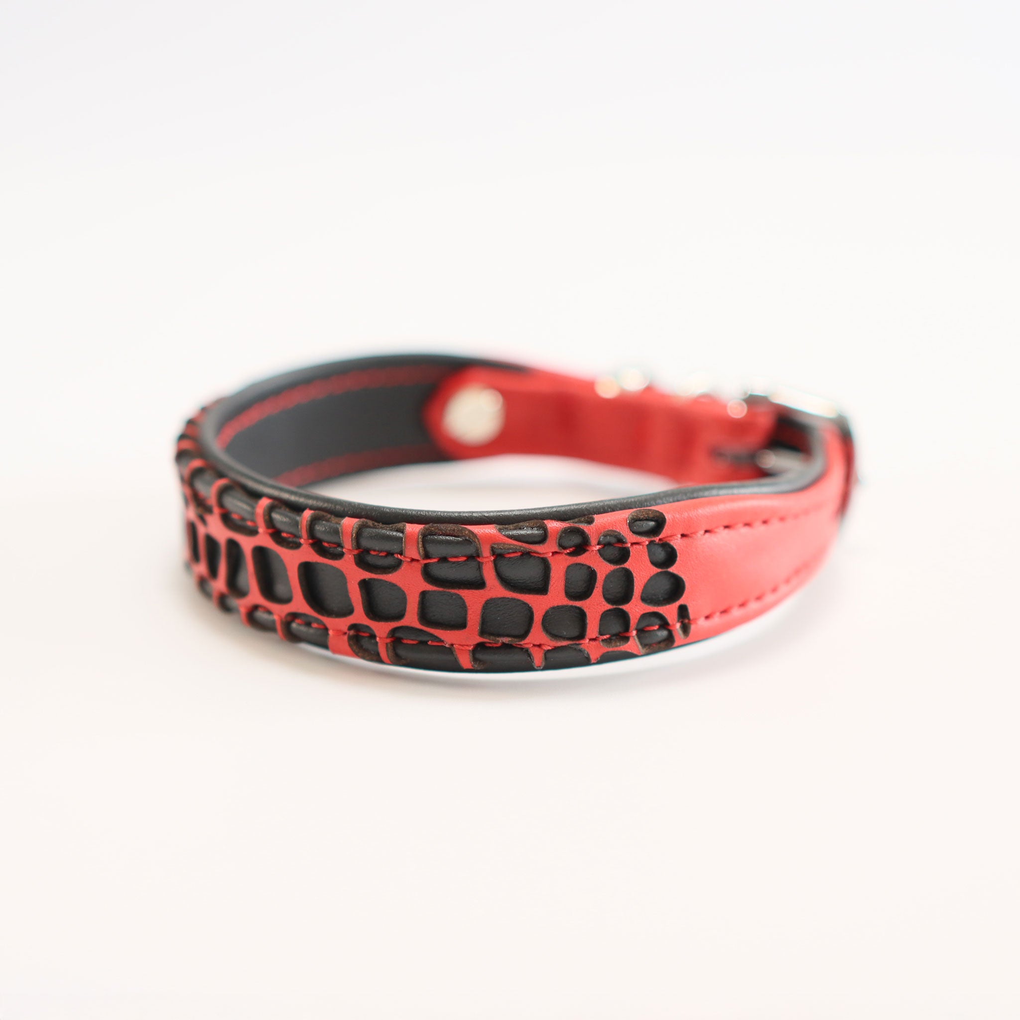 Detailansicht eines roten Hundehalsbandes aus Leder mit schwarzen laser-geschnittenen Panzerplatten