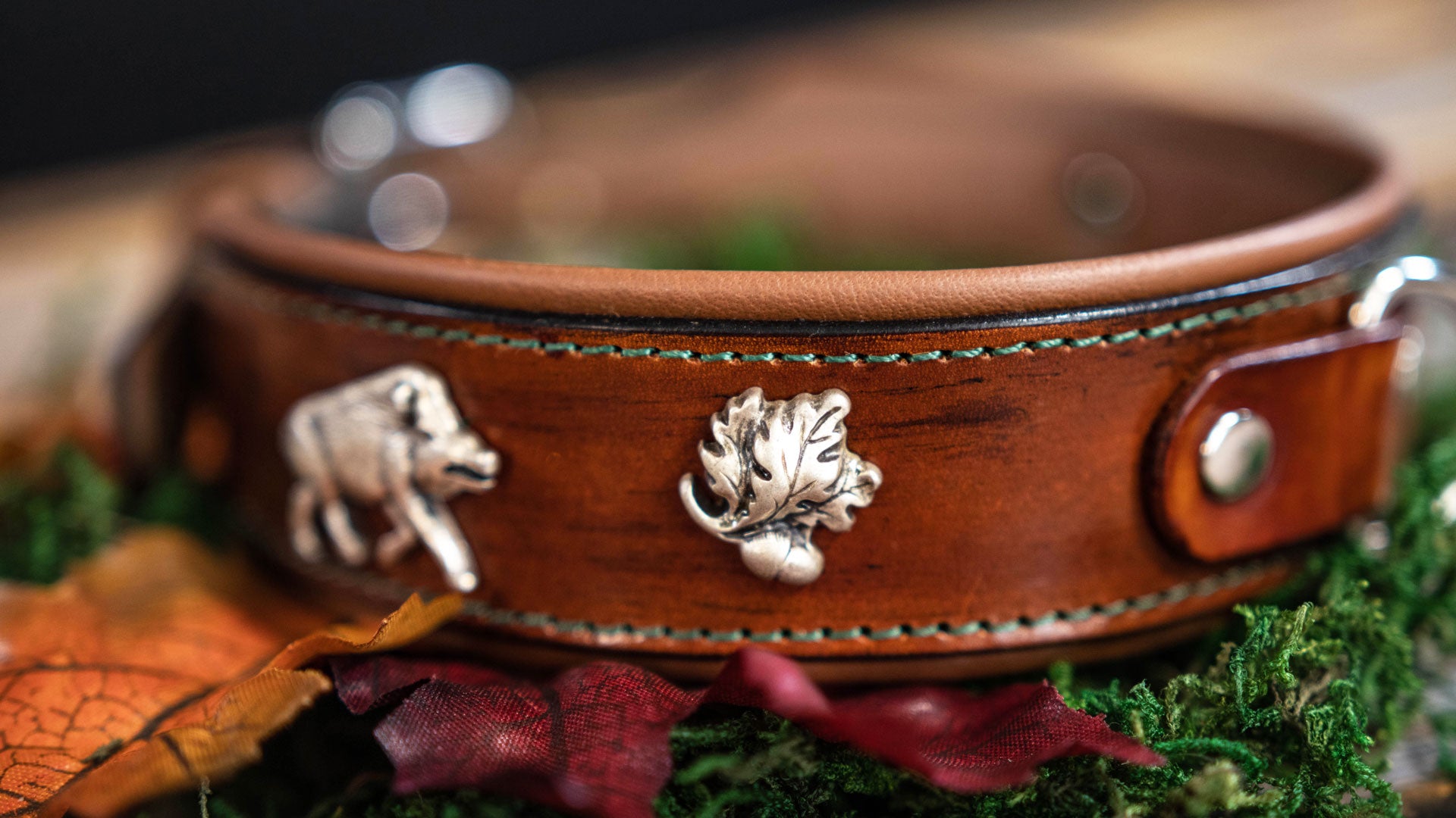 detailansicht von silbernem eichenlaub auf einem braunen lederriemen mit antique finish