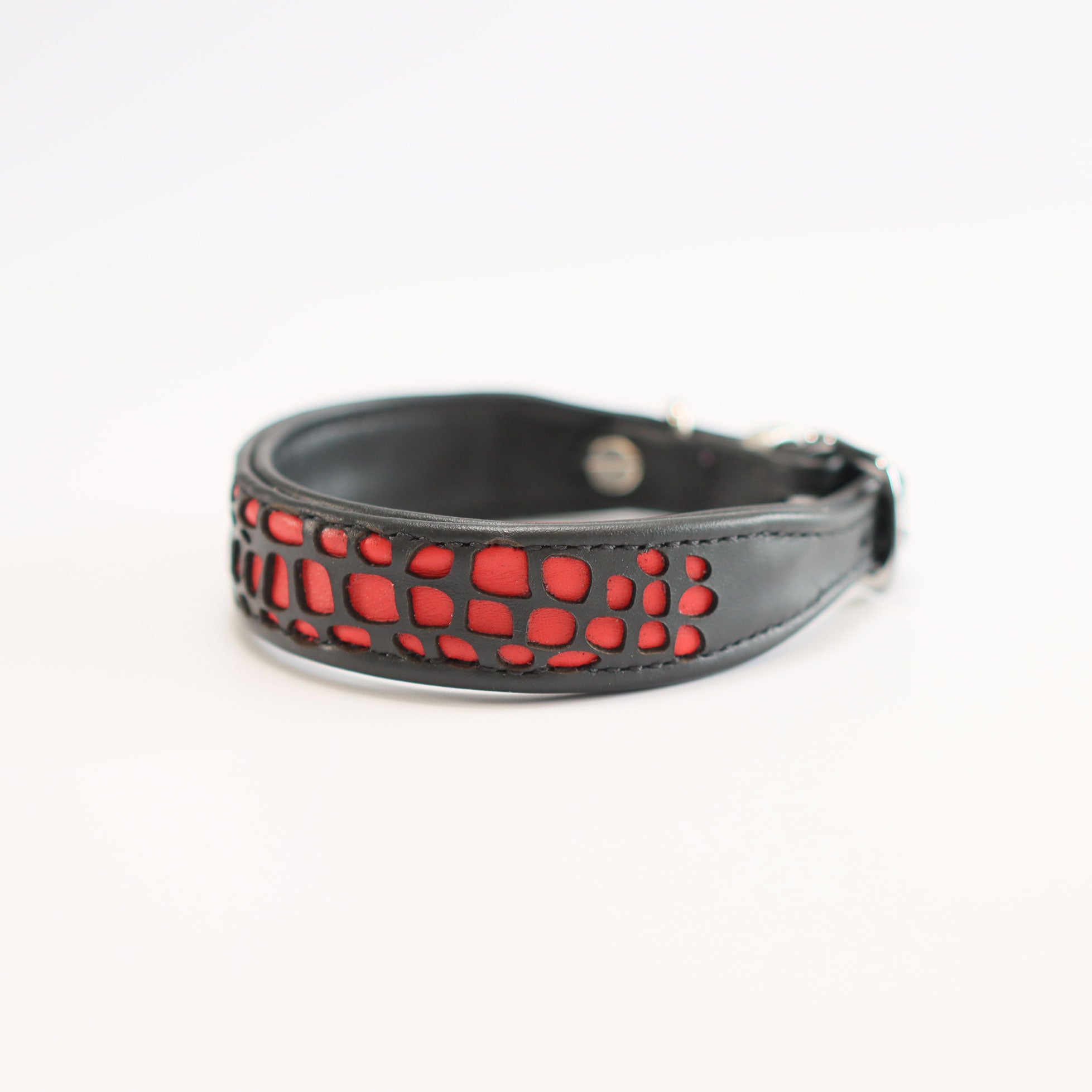 Detailansicht eines schwarzenn Hundehalsbandes aus Leder mit roten laser-geschnittenen Panzerplatten