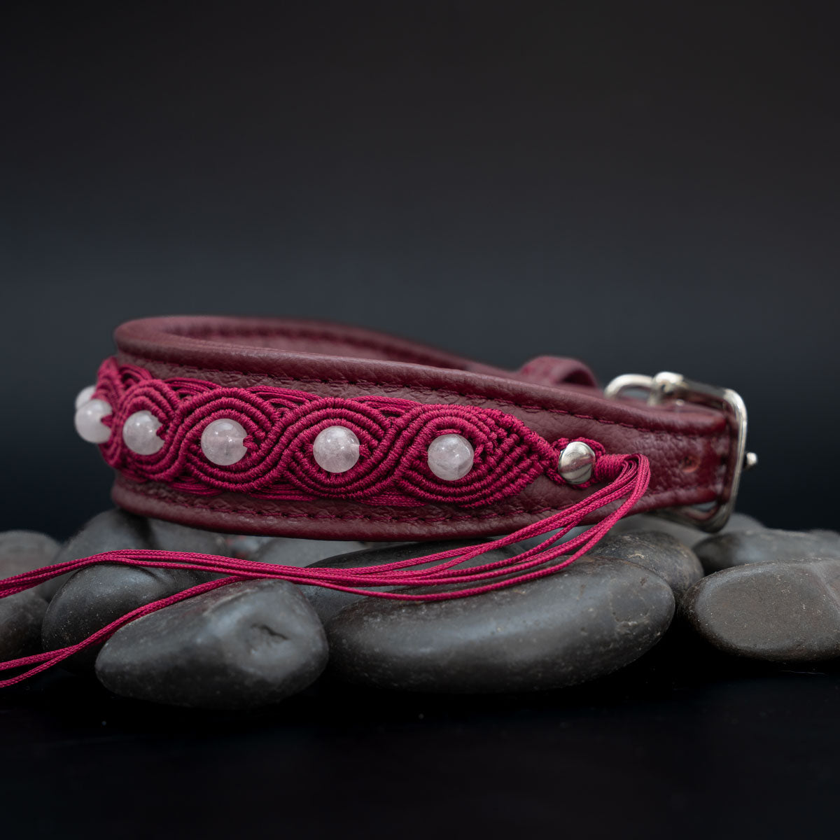 Rubinrotes Lederhalsband mit Rosenquarz in ovalen Makramee-Motiven, Schnalle rechts und langen Garnenden im Vordergrund.