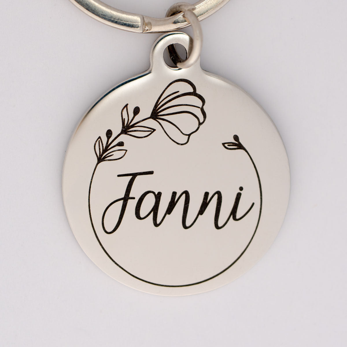 personalisierte Edelstahl Hundemarke mit dem Rufnamen Fanni und einer Mohnblüte darum