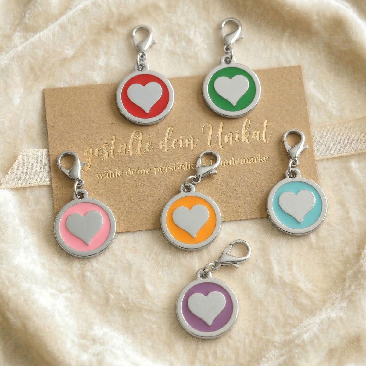 Übersicht verschiedenfarbiger Hundemarken mit Herz-Motiv und Gravur-Option in Rot, Rosa, Blau, Orange, Lila und Grün.