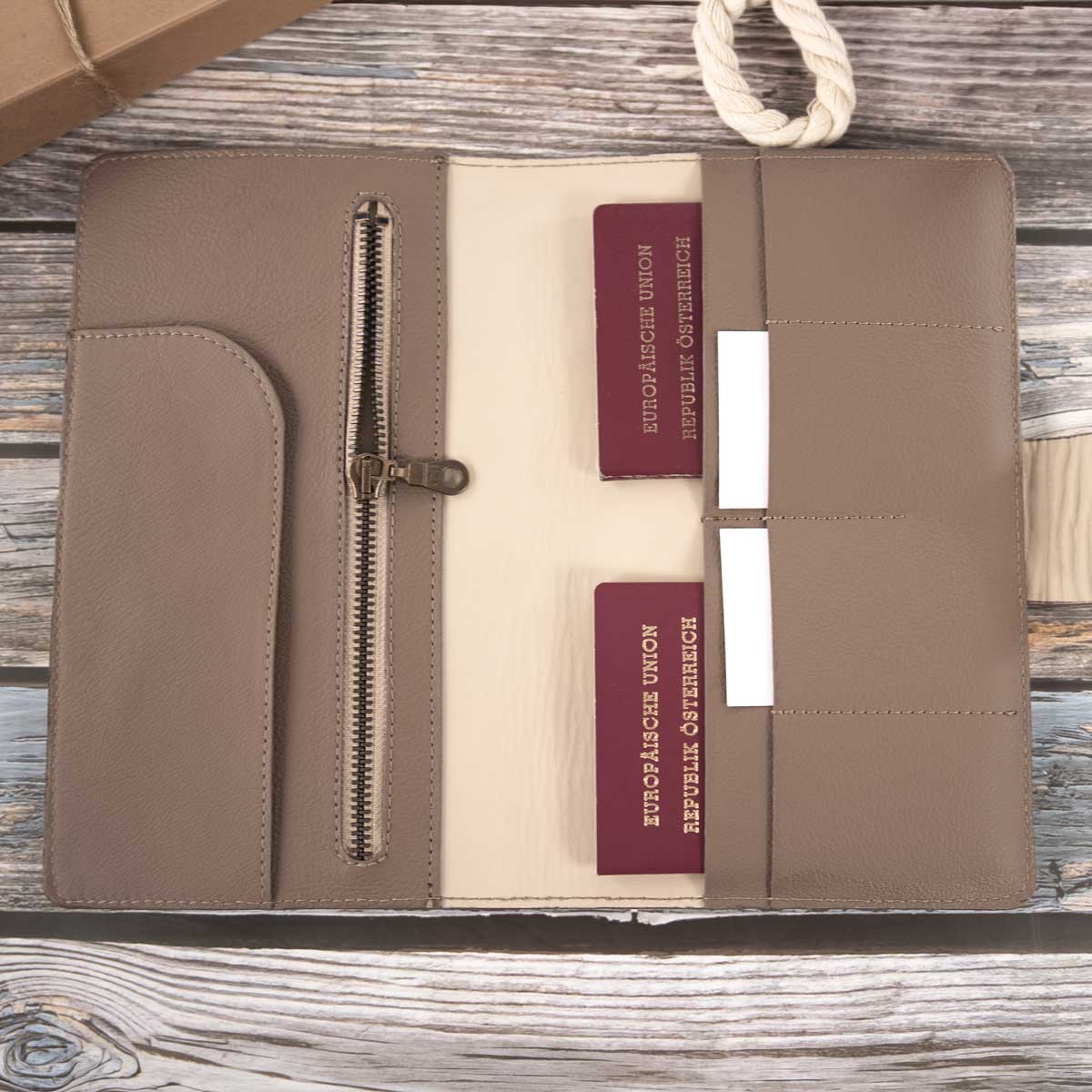 Geöffnetes Leder Travel Wallet in Taupe und Beige, befüllt mit zwei Reisepässen, Karten und geöffnetem Reißverschluss