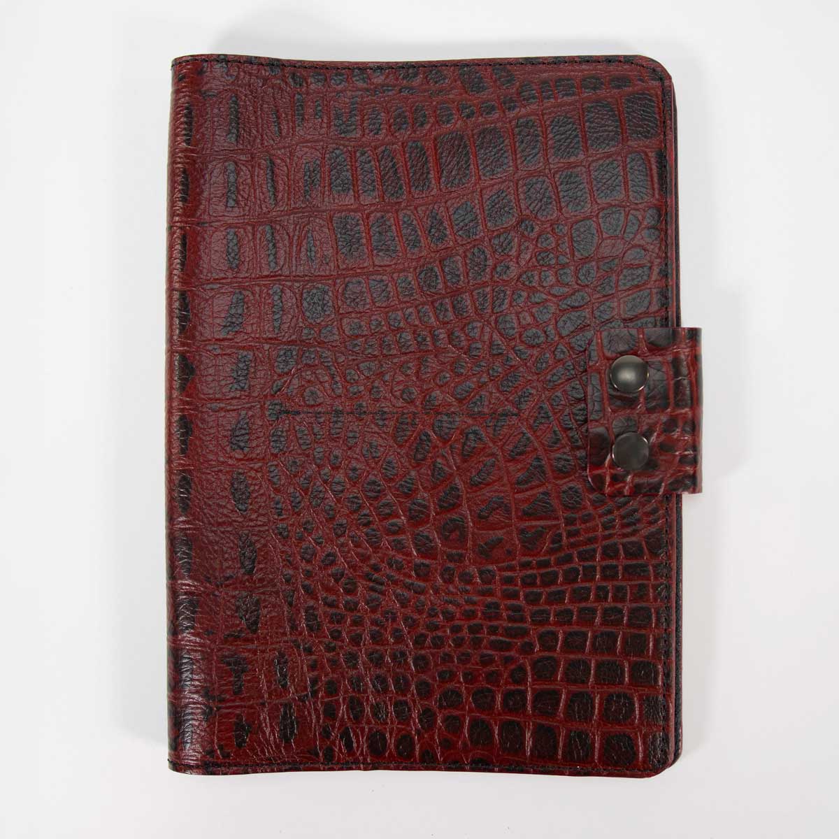 Geschlossenes Travel Wallet für vier Pässe aus aufregendem rot-schwarzem Kroko-Leder. Sichtbar ist die markante Verschlusslasche mit antik-messingfarbenem Druckknopf