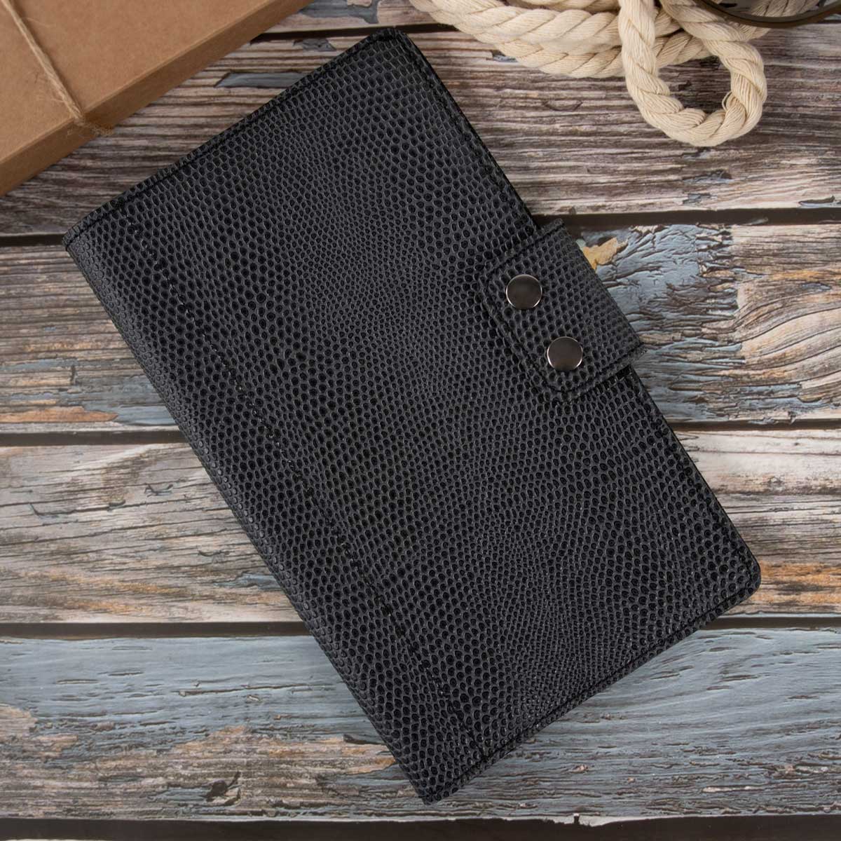 Geschlossenes Travel Wallet aus schwerem, asphaltgrauem italienischem Taschenleder mit feiner Echsenprägung. Der Verschluss erfolgt durch zwei elegante, gunfarbene Druckknöpfe.
