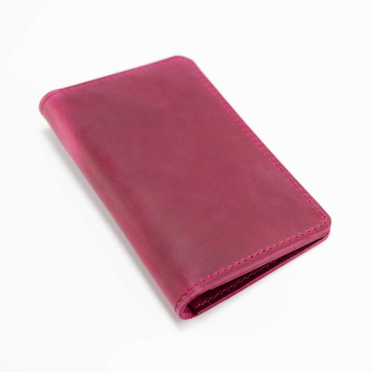 Geschlossene Leder-Reisepasshülle in Wild Berry, schräg fotografiert, zeigt das puristische Design ohne Verschlusslasche.