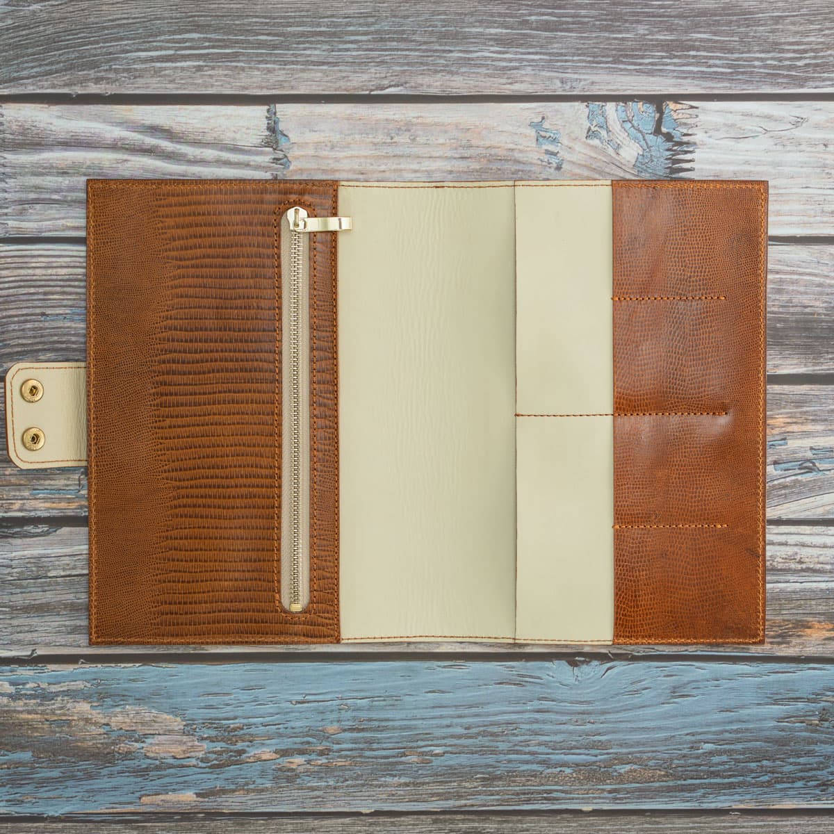 Geöffnetes Travel Wallet aus Leder mit elegantem Innenfutter in Creme. Die durchdachte Aufteilung zeigt vier Kartenfächer, Steckplätze für Reisepässe und ein großes Reißverschlussfach.