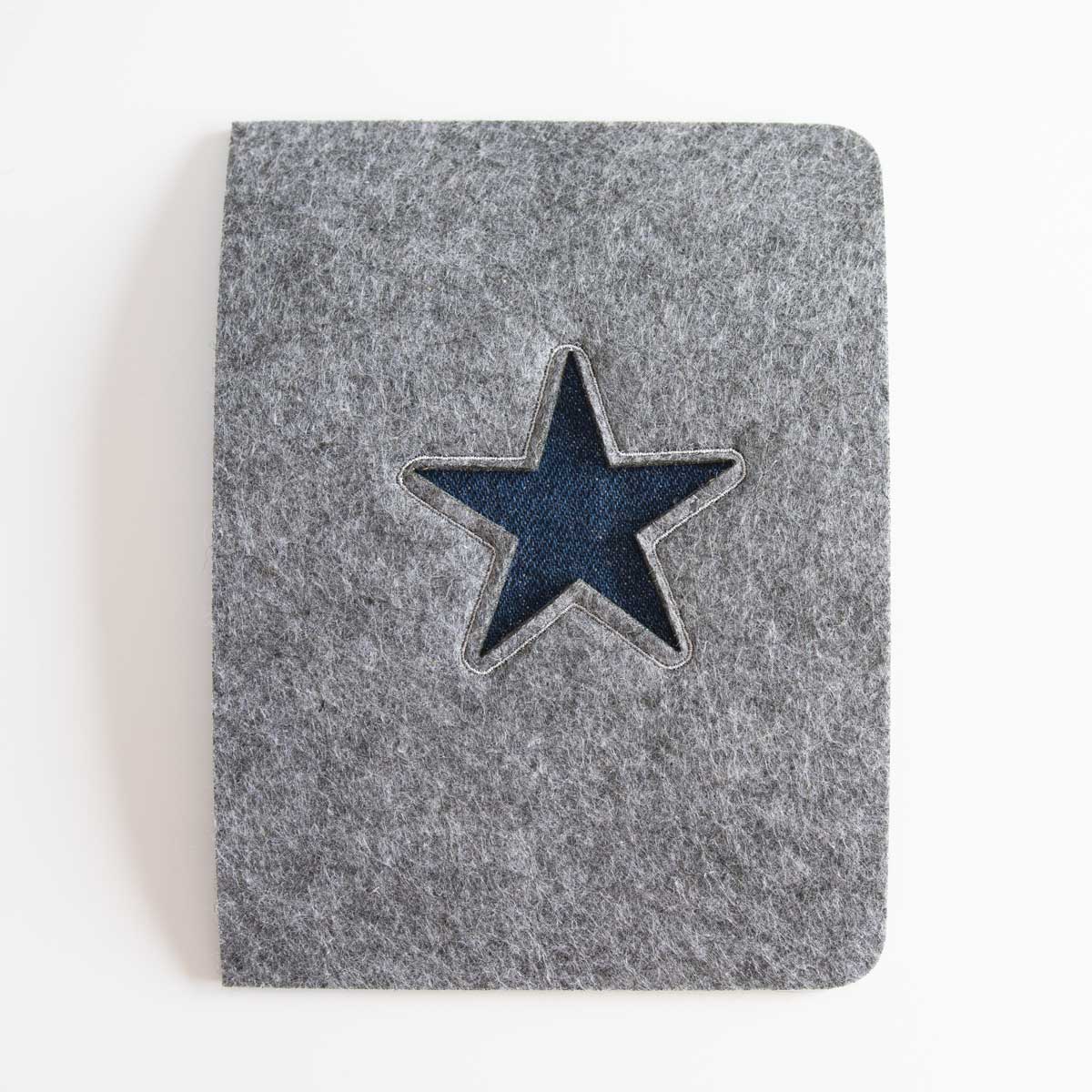 Beispiel für die Unterlegung des Stern-Lasercuts mit blauem Denim-Stoff bei der handgefertigten Kombi-Impfpasshülle.