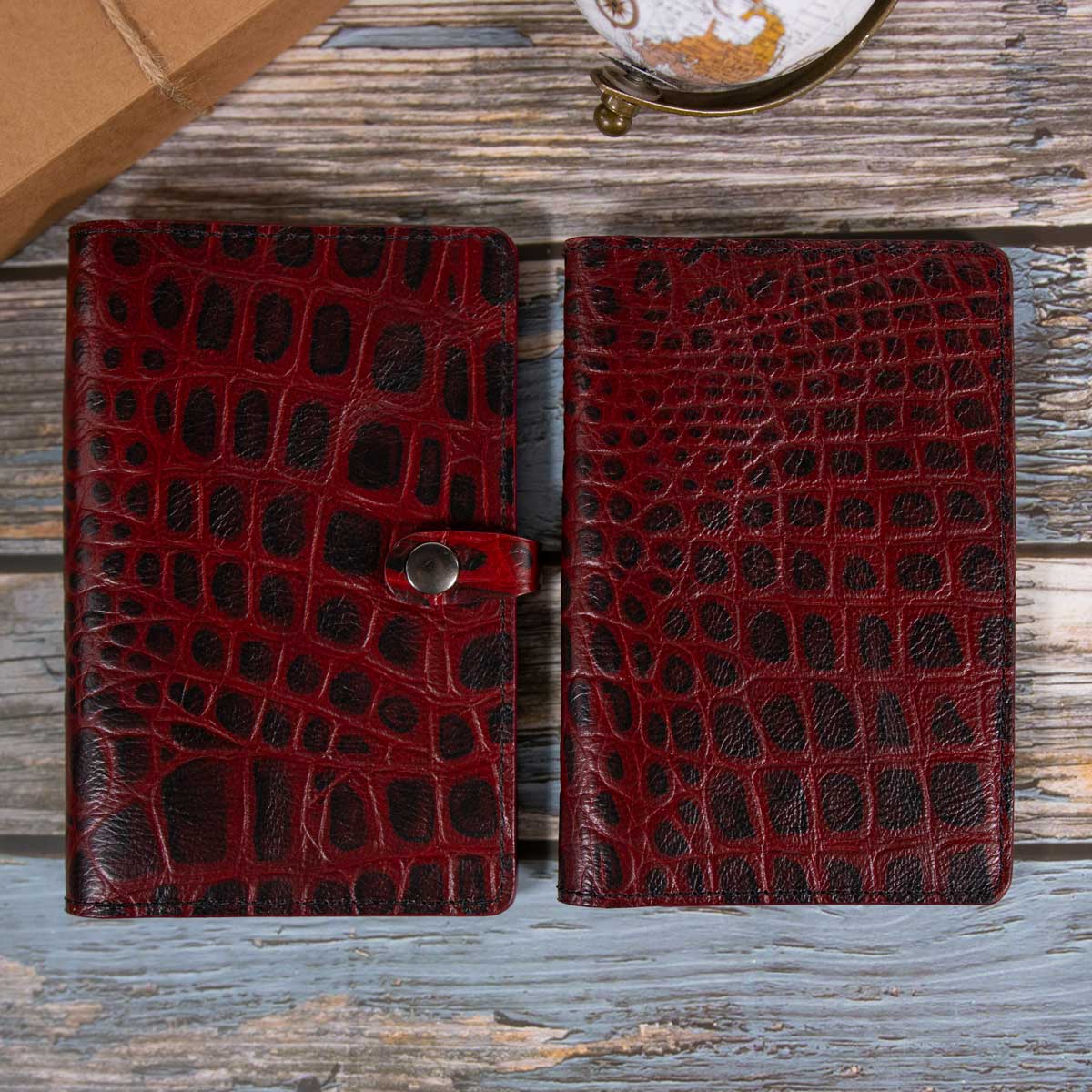 Größenvergleich der rot-schwarzen Kroko-Leder Kollektion: rechts die klassische Reisepasshülle für Menschen, links die passgenaue, etwas größere Hülle mit Verschlusslasche für den EU-Heimtierausweis.