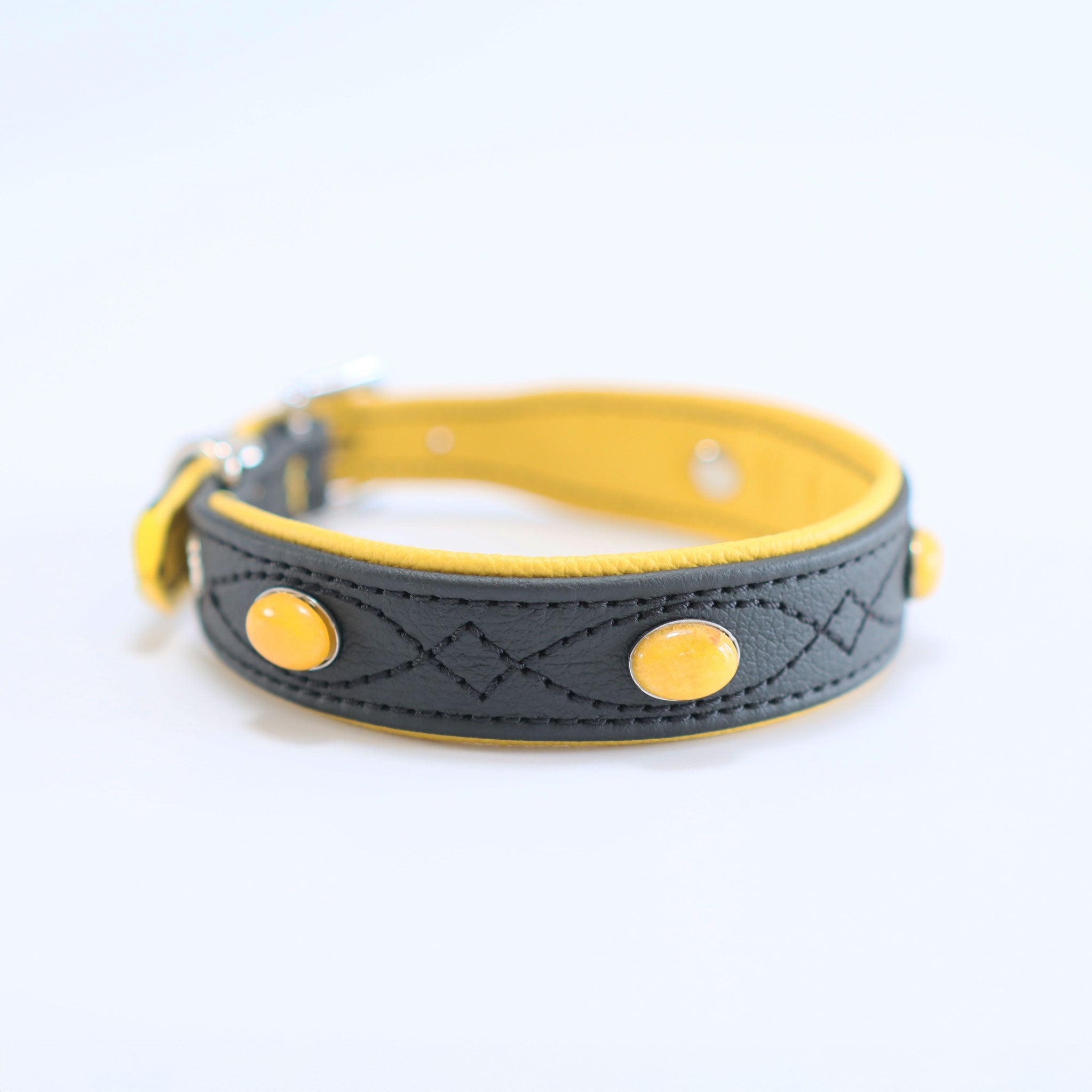 Elegantes schwarz-gelbes handgefertigtes Halsband mit gelben Steinen liegt auf einem Studiohintergrund