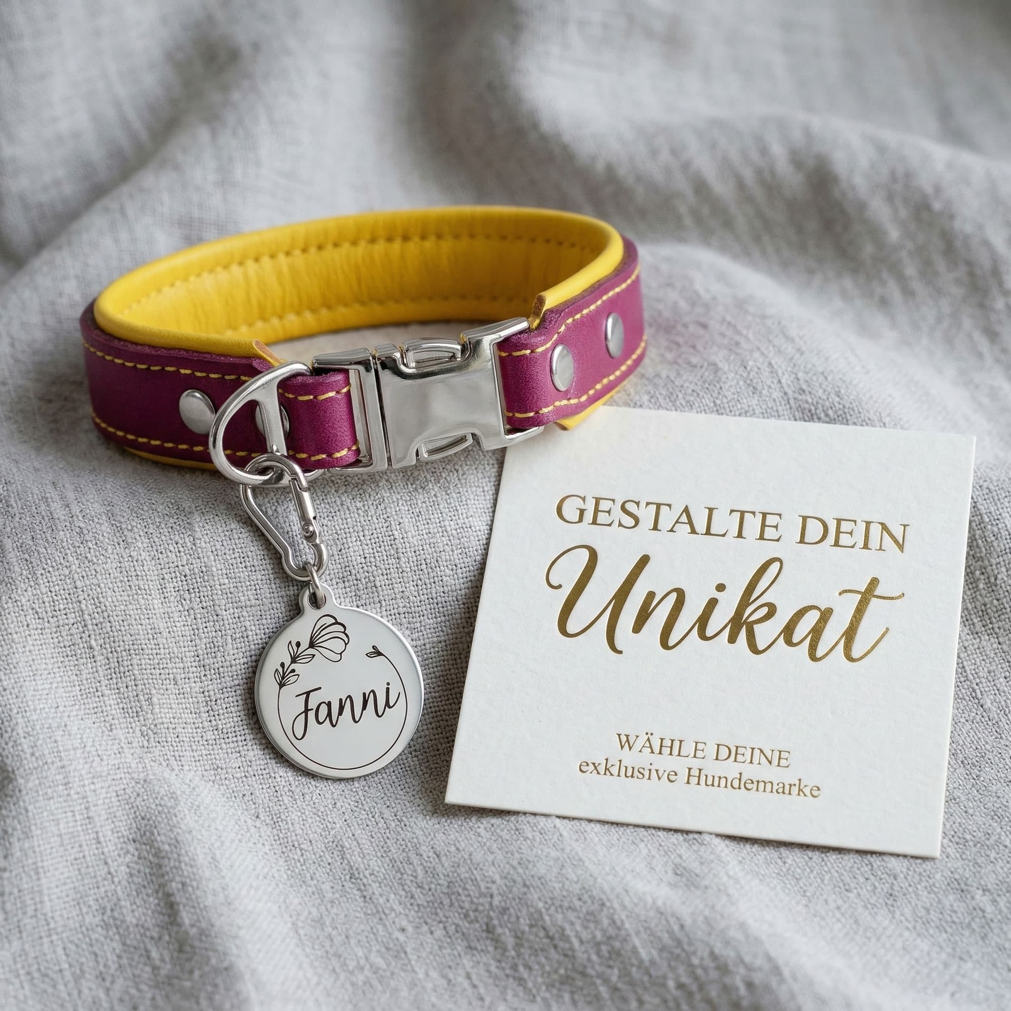 personalisierte Edelstahl Hundemarke angebracht an einem Halsband. auf der Hundemarke ist der Namen Fanni und eine Mohnblume daneben liegt eine Karte im Boutique Stil und der Aufforderung deine Hundemarke zu gestalten