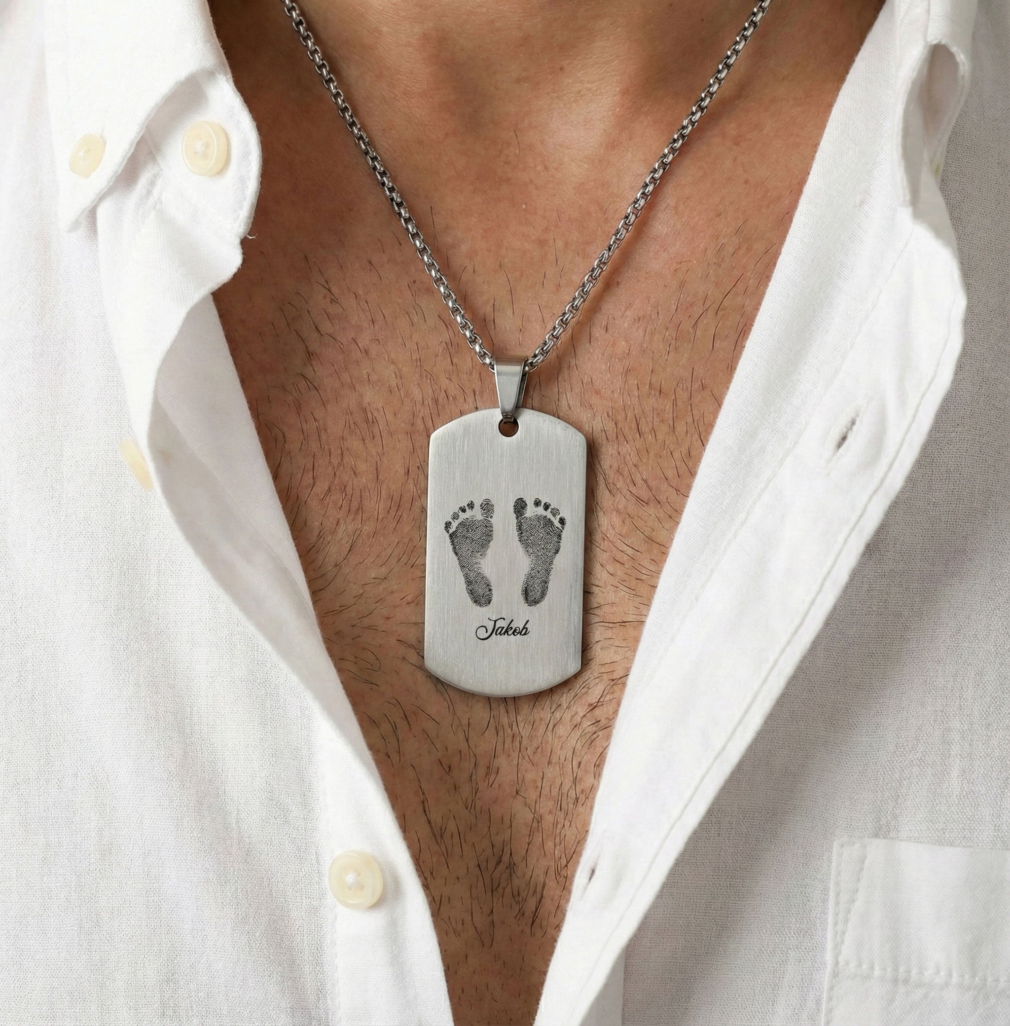 gravierter Herren-Kettenanhänger mit babyfüßen und dem Namen Jakob ein mann trägt diese Kette er trägt ein weißes Hemd