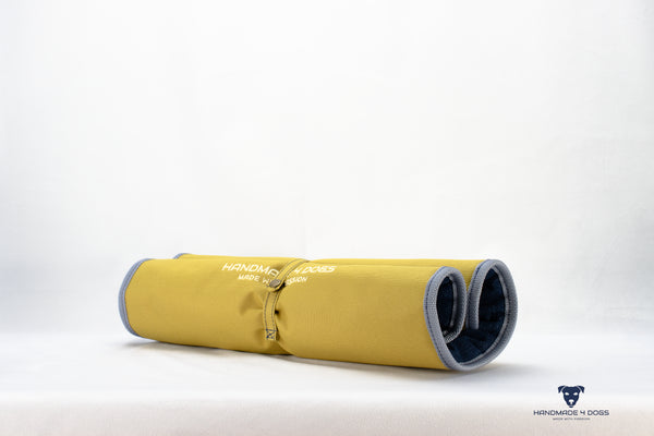 aufgerolltes-handgefertigtes-Hunde-Reisebett-von-handmade-4-dogs-in-der-Farbe-Senf-mit-wedgwood-farbiger-Einfassung-und-einer-Liegefläche-aus-dunklem-Denim