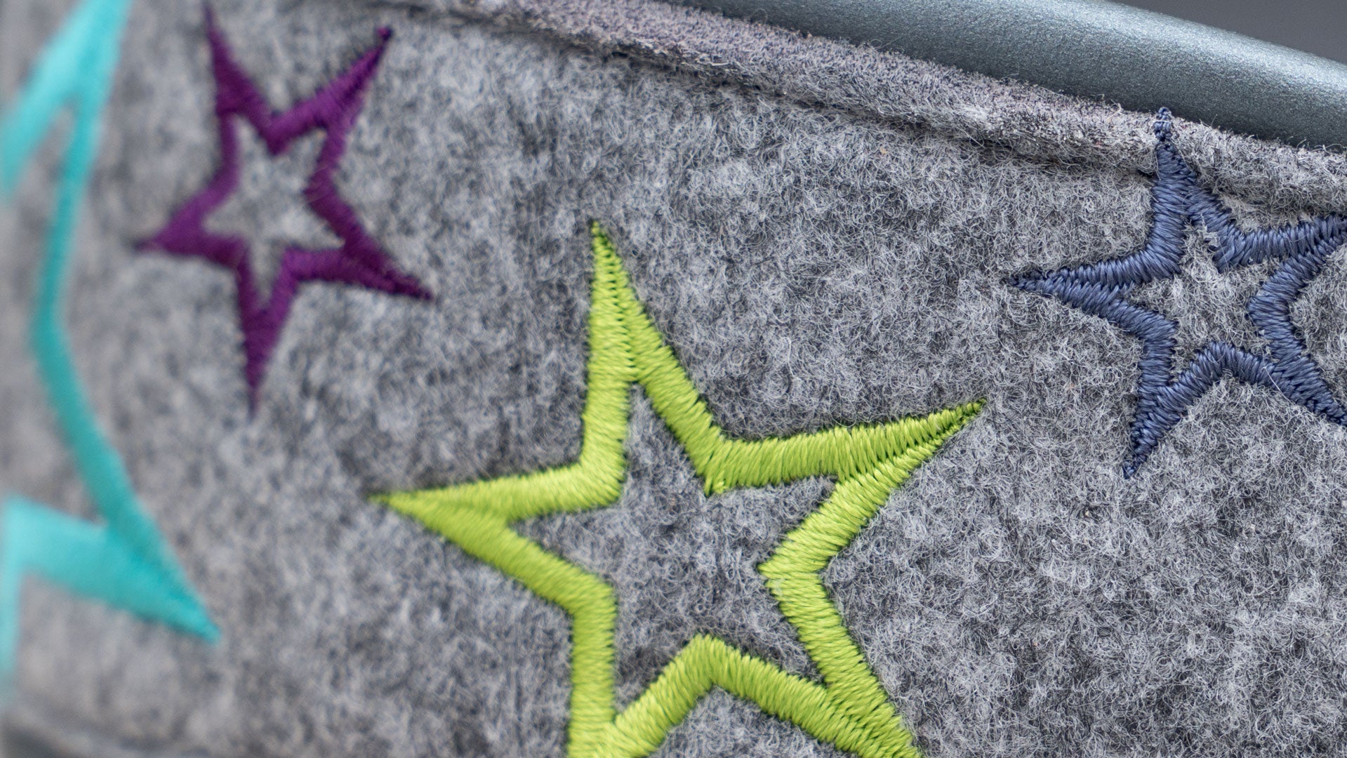 Nahaufnahme der hochwertigen Multicolor-Sternenstickerei auf grauem Taschenfilz