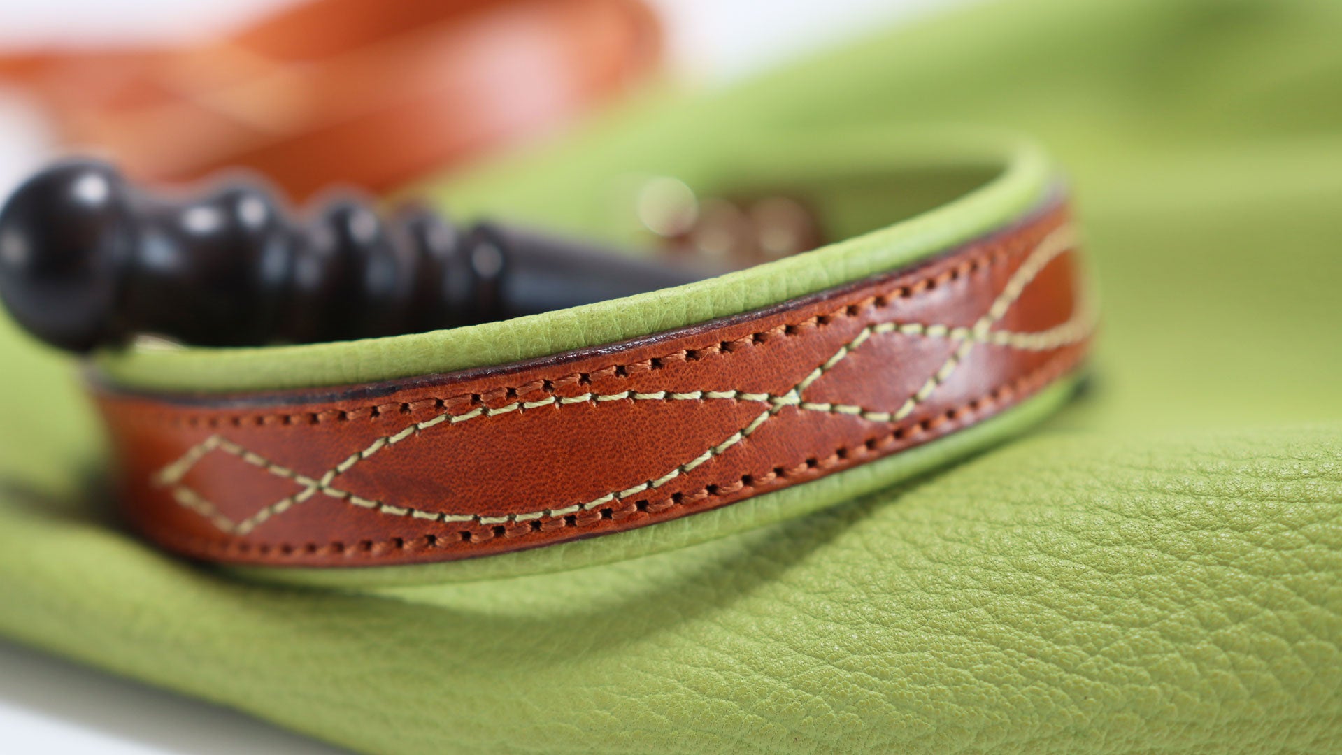 Makroaufnahme der grünen Steppnaht in Gunslinger-Form auf braunem Lede