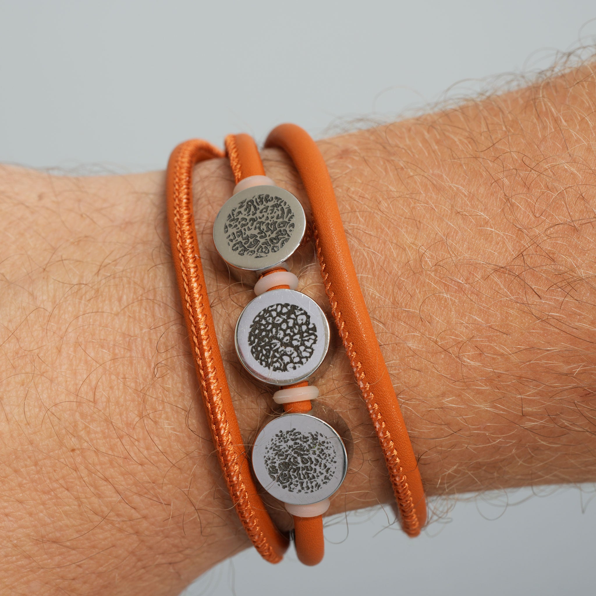Dreifach gewickeltes Lederarmband in Cognac mit drei silbernen Elementen und personalisierter Gravur am Arm
