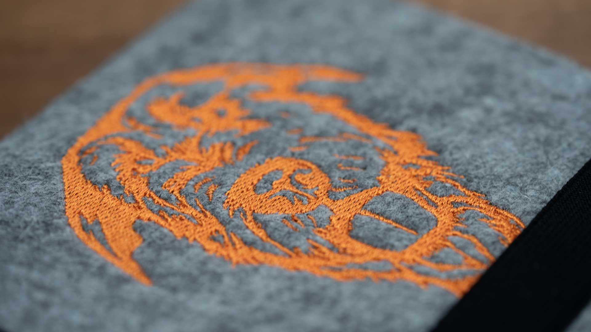 Makroaufnahme der orangefarbenen Irish-Wolfhound-Stickerei auf grauem Wollfilz