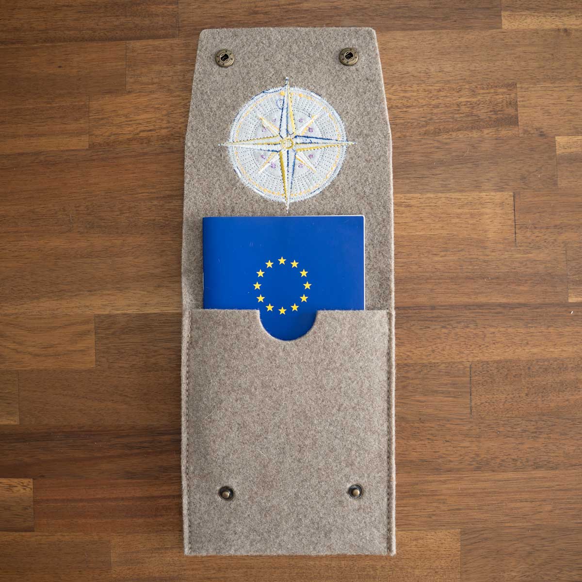 Geöffnete Heimtierausweis Hülle mit eingeschobenem EU-Heimtierausweis und Kompassrose-Stickerei