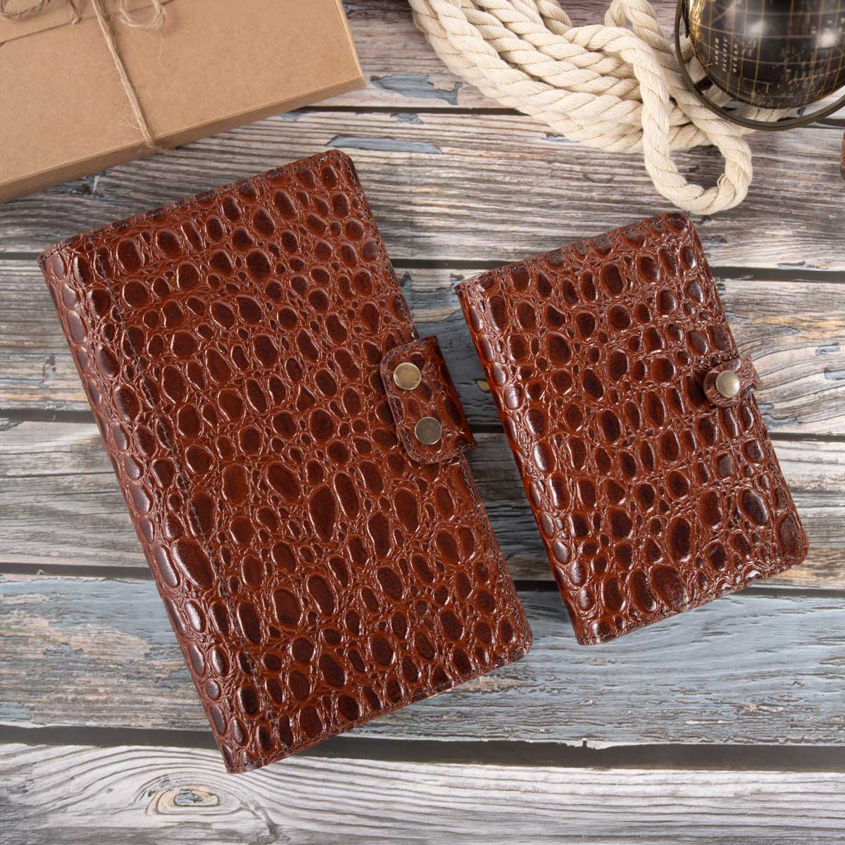 Gegenüberstellung des whiskey-farbenen Travel Wallets und einer passenden EU-Heimtierausweishülle, die den deutlichen Größenunterschied der Etuis verdeutlicht